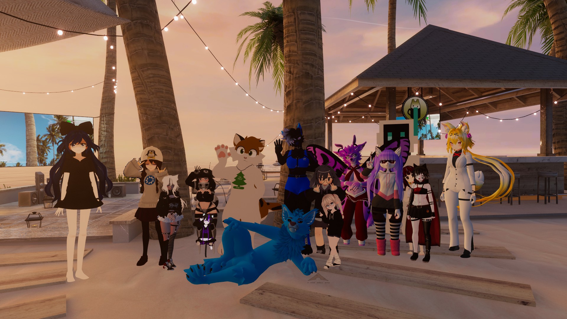 A group of diverse, anthropomorphic and anime-style characters gathered on a sandy beach at sunset. There are fifteen characters in total, with one large blue furry character lying on the ground in the foreground. The other characters are standing behind or around the blue character. The background features palm trees, string lights, and a beach bar or cabana. The sky is a warm gradient of orange and pink, indicating sunset. The characters exhibit a variety of styles, including cat-like features, wings, and different outfits. One character on the far left has long dark hair and a black dress, while another on the far right has long blonde hair, fox ears, and a white suit. The overall mood is casual and social.